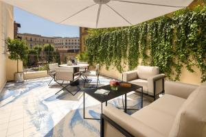 a patio with tables and chairs and a green wall at art'otel Rome Via Veneto in Rome