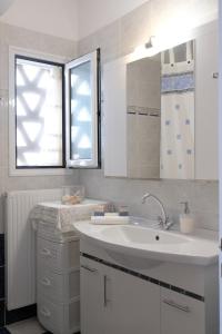 a white bathroom with a sink and a window at Exohiko in Aliki