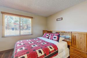 ein Schlafzimmer mit einem Bett mit einer Decke und einem Fenster in der Unterkunft Meadow-Front Metcalf Bay Gem #542 in Big Bear Lake