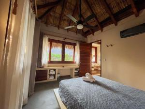 a bedroom with a bed with a ceiling fan and a window at Paraíso del Surf, A 50m de las Olas Perfectas, AC, Starlink, Piscina, La Saladita surf in La Salada
