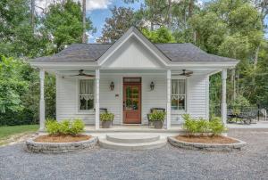 a white house with a front porch with plants at Elledot Cottage in Summerville