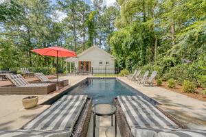 a swimming pool with chairs and an umbrella at Elledot Cottage in Summerville