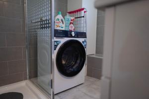 a washing machine in a bathroom with a shower at Azorean Stays T1-Relaxing 1-Bedroom Retreat Near São Miguel Highlights in Lomba da Cruz