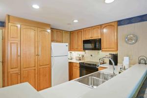 a kitchen with wooden cabinets and a white refrigerator at Lodge Tower 594 One Bedroom Residence in Vail