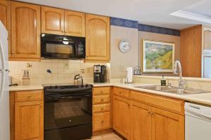 a kitchen with wooden cabinets and a stove and a sink at Lodge Tower 594 One Bedroom Residence in Vail