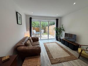 a living room with a leather couch and a television at Entire Home close to Peppa Pig World & New Forest in Totton