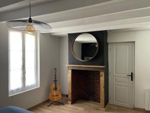 a room with a fireplace with a mirror and a guitar at Maison du bonheur in Combres