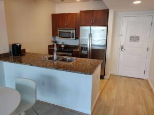 a kitchen with a sink and a refrigerator at Modern bedroom in great condo! Beach Pass incl! in Boynton Beach