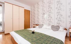 a bedroom with a white bed with a green blanket at Apartman Izi Green s pogledom na more in Kornić