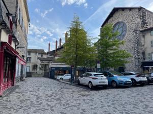 una strada di ciottoli con auto parcheggiate di fronte a un edificio di Maison Côté Halle L'Artiste a Saint-Flour