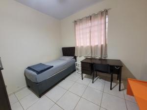 a bedroom with a bed and a desk and a window at Casa no centro! in Campo Mourão