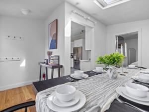 a dining room with a table with white dishes on it at Boston 4BR Home with Parking BBQ Fire in Somerville