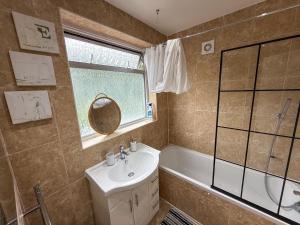 a bathroom with a sink and a tub and a mirror at Bassetts House - Contractor ready! in Farnborough +24 photos