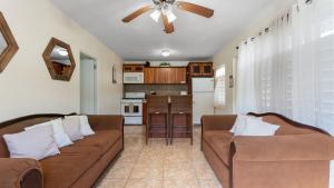 a living room with two brown couches and a kitchen at The Reef 1 walking disntance to Steps Beach in Rincon