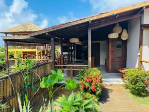 a house with a wooden deck and flowers at Pousada Ilha Bella in Fernando de Noronha