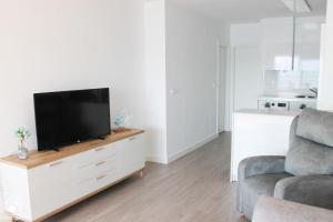 sala de estar con TV de pantalla plana en un centro de entretenimiento blanco en Miramar Puerto Bello, en La Manga del Mar Menor