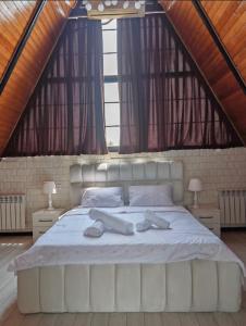 a large white bed in a room with windows at Huzoor Aframe Gabala in Gabala