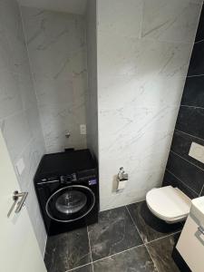 a bathroom with a washing machine and a toilet at Studio moderne avec parking in Delémont