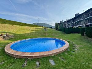 a large blue pool in a grassy yard at Ático duplex a pie de pistas de esquí in La Molina
