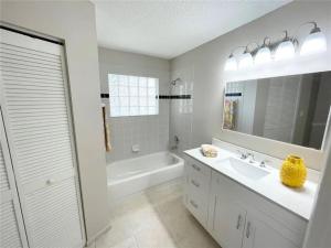 a white bathroom with a tub and a sink and a mirror at Relaxing Getaway in Sarasota Great Location Whole House in Sarasota +51 photos