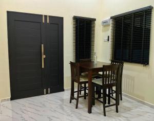 a dining room with a table and chairs and black doors at Homestay Mini in Bukit Payong