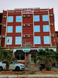 un hotel rojo con coches estacionados frente a él en HOTEL Bab El Madina, en Adrar