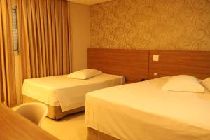 a hotel room with two beds and a chair at Indaiá Park Hotel in Campo Grande