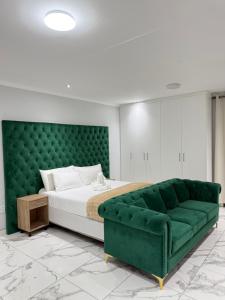 a bedroom with a green bed and a green couch at Malrose guesthouse Tours And safaris Windhoek Namibia Airport Shuttle services available in Windhoek