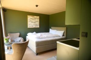 a green room with a bed and a chair at Hytte Blåtind, Rekkedal Gjestegard - Sæbø in Sæbø