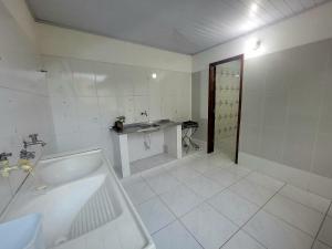 a white bathroom with a sink and a tub at Quarto Compartilhado na Praça de Serra Grande in Uruçuca