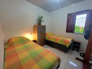 a bedroom with two beds and a window at Quarto Compartilhado na Praça de Serra Grande in Uruçuca