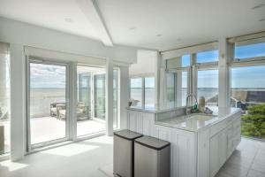 a white kitchen with a sink and glass windows at Waterfront Hot Tub Sauna Private Beach in Wellfleet