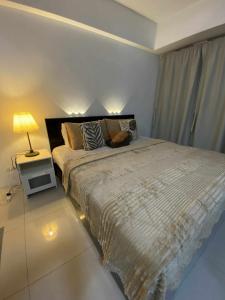 a bedroom with a large bed and a lamp on a table at Bekipay Suite at One Palm Tree right across NAIA 3 in Manila +9 photos