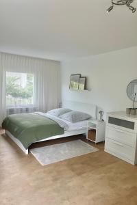 een witte slaapkamer met een bed en een bureau bij REHBLICK Ferienwohnung in Trösel