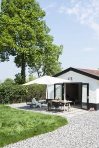 a patio with a table and an umbrella at Vakantiehuisjes Theodorus en Josephine - Landgoed Heerdeberg- Maastricht in Cadier en Keer