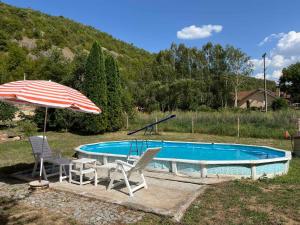 a swimming pool with two chairs and an umbrella at Vila Petrov in Lukavica