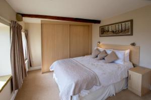 una camera da letto con un letto con lenzuola e cuscini bianchi di Weavers Cottage a Cowling