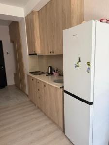 Una cocina con refrigerador blanco y gabinetes de madera. en Didveli Residence Apartment, en Bakuriani