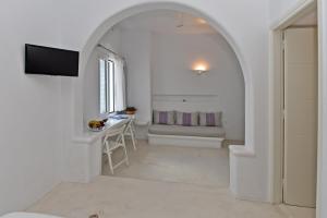 a room with an archway with a table and a television at Eleftheria Veloudiou in Tinos Town