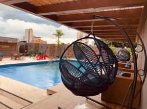 a basket swing hanging over a swimming pool at Flat Apart Hotel Crystal Place - apto 905 in Goiânia