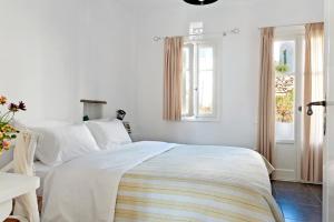 a white bedroom with a bed and a window at Skaris Guesthouse Tinos in Panormos