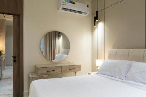a bedroom with a white bed and a mirror at Söz suites in Al Khobar