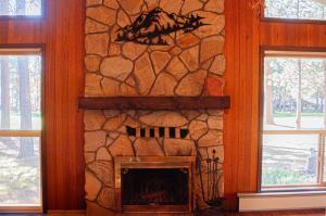 a stone fireplace in a room with two windows at Golf Home 010 in Black Butte Ranch