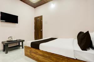 een slaapkamer met een bed en een tafel met een televisie bij HOTEL O SKYLITE Vhirgaon in Pānchgaon