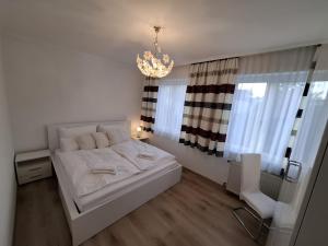 une chambre avec un lit blanc et un lustre dans l'établissement Haabsburg Appartment Vienna 6 Personen, Balkon, voll ausgestattete Küche, Grün-Ruhelage am Stadtrand, gute Öffi Anbindung, à Vienne