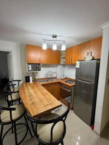 a kitchen with a wooden table and a refrigerator at Departamento Pucón 4 personas in Pucón