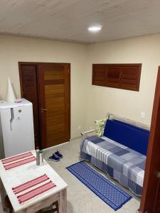 a room with a bed and a table and a refrigerator at Casa Barra do Camaratuba in Mataraca