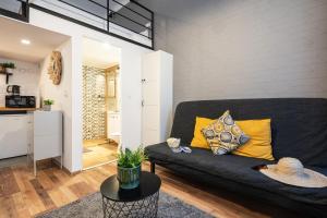 a living room with a black couch and a kitchen at Funhouse Dob in Budapest