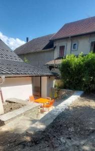 a patio with two chairs and a table in front of a house at APPARTEMENT 4 PERSONNES 100 metres du Lac jardin privé in Doussard +8 photos