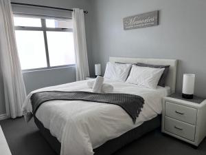 Un dormitorio con una gran cama blanca con ventana. en EasyCapeTown - Entire Flat in Big Bay, en Cape Town